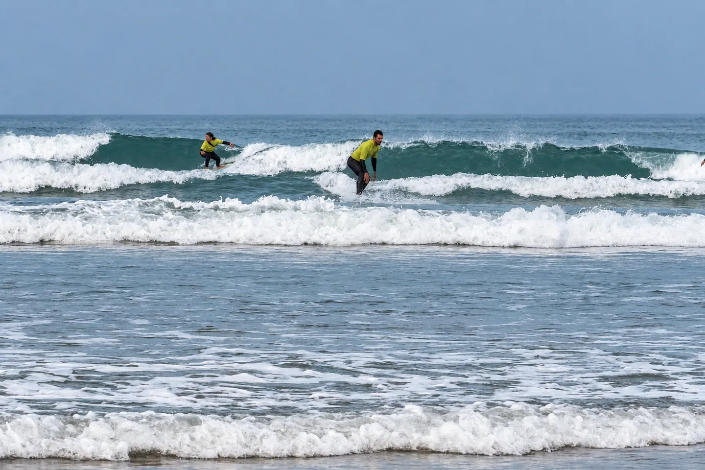 Grupo de surfistas caminando hacia el mar al amanecer